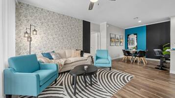 A modern living room with a sofa, armchairs, a coffee table, and a dining area with chairs and a table.