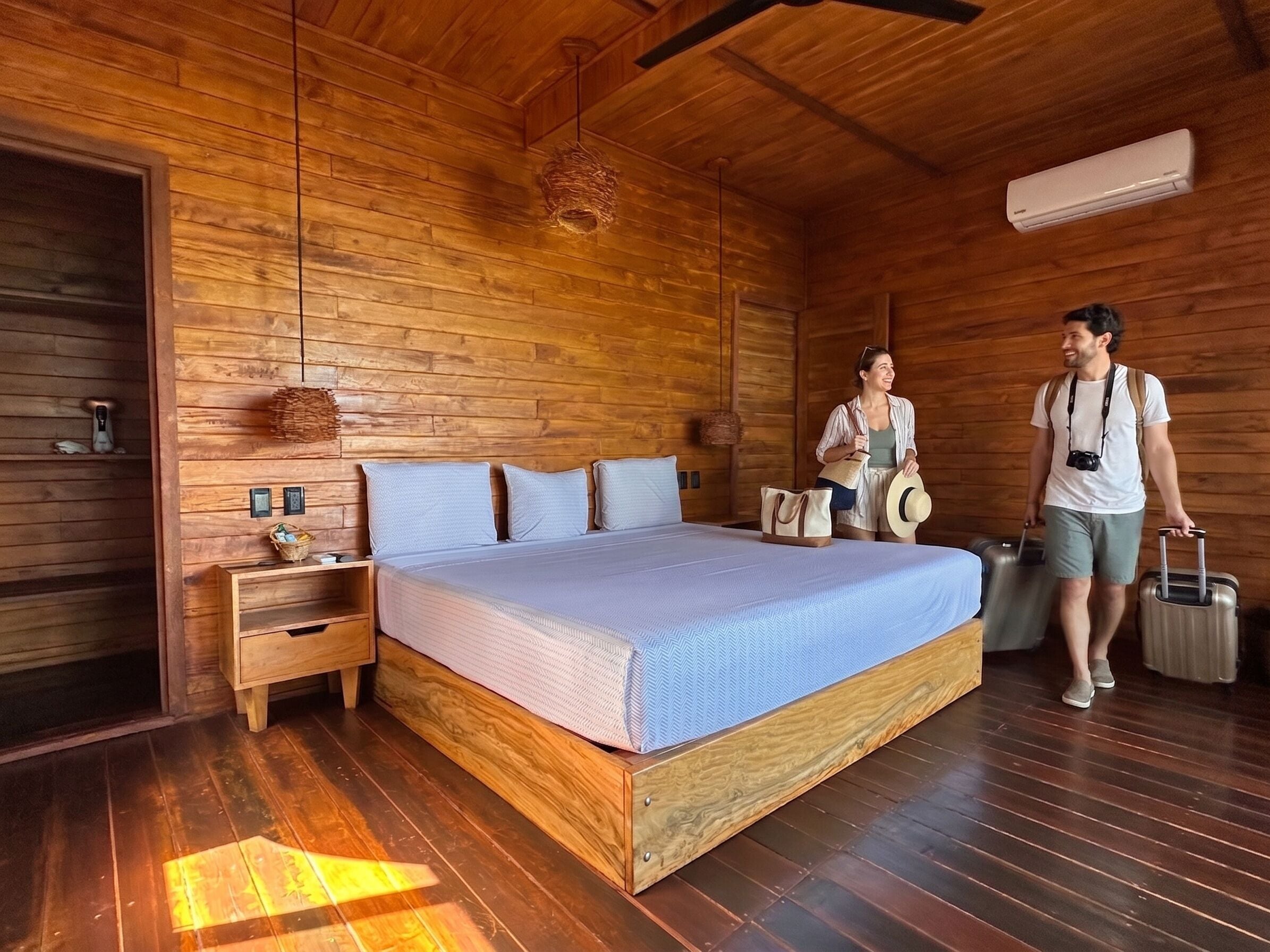 A wooden-paneled room with a bed, bedside tables, and a hanging light fixture.