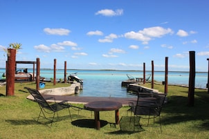 Un área de descanso frente a la playa con piscina, sillones y una mesa.