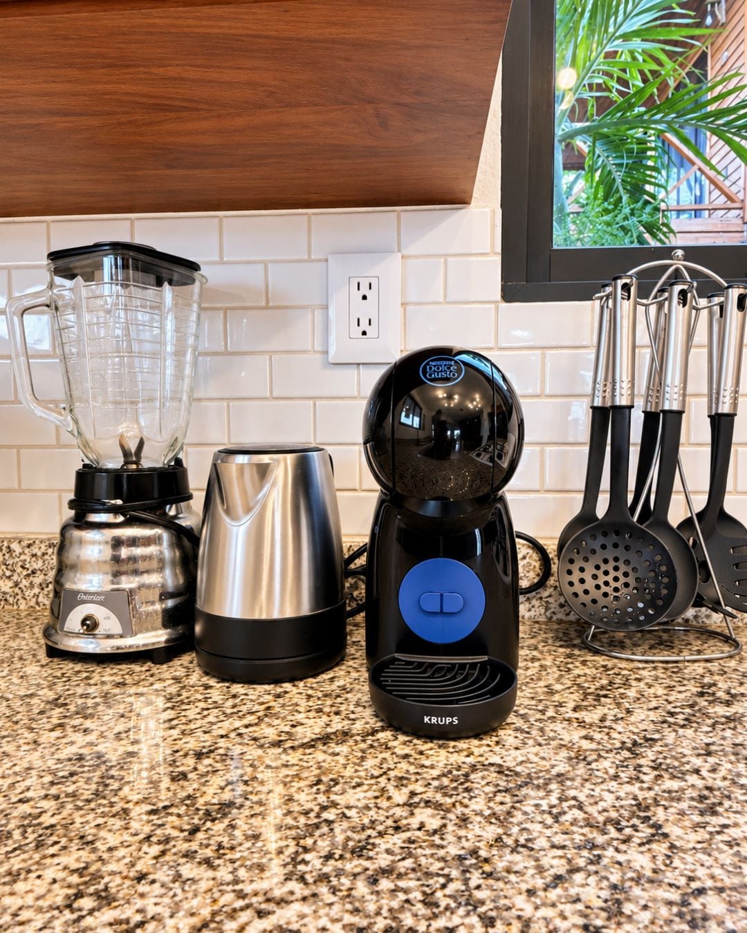 Un plan de travail de cuisine avec un mixeur, une machine à café et une cafetière Krups.
