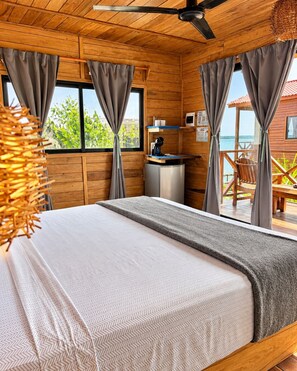 Habitación de cabaña de madera con una cama, un escritorio y vistas al mar.