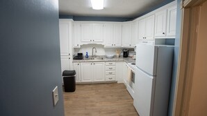 Una cocina compacta con armarios blancos, un lavamanos, una estufa y un refrigerador.
