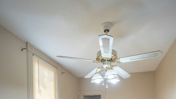 Un dormitorio con dos camas, ventilador de techo y ventana con persianas.