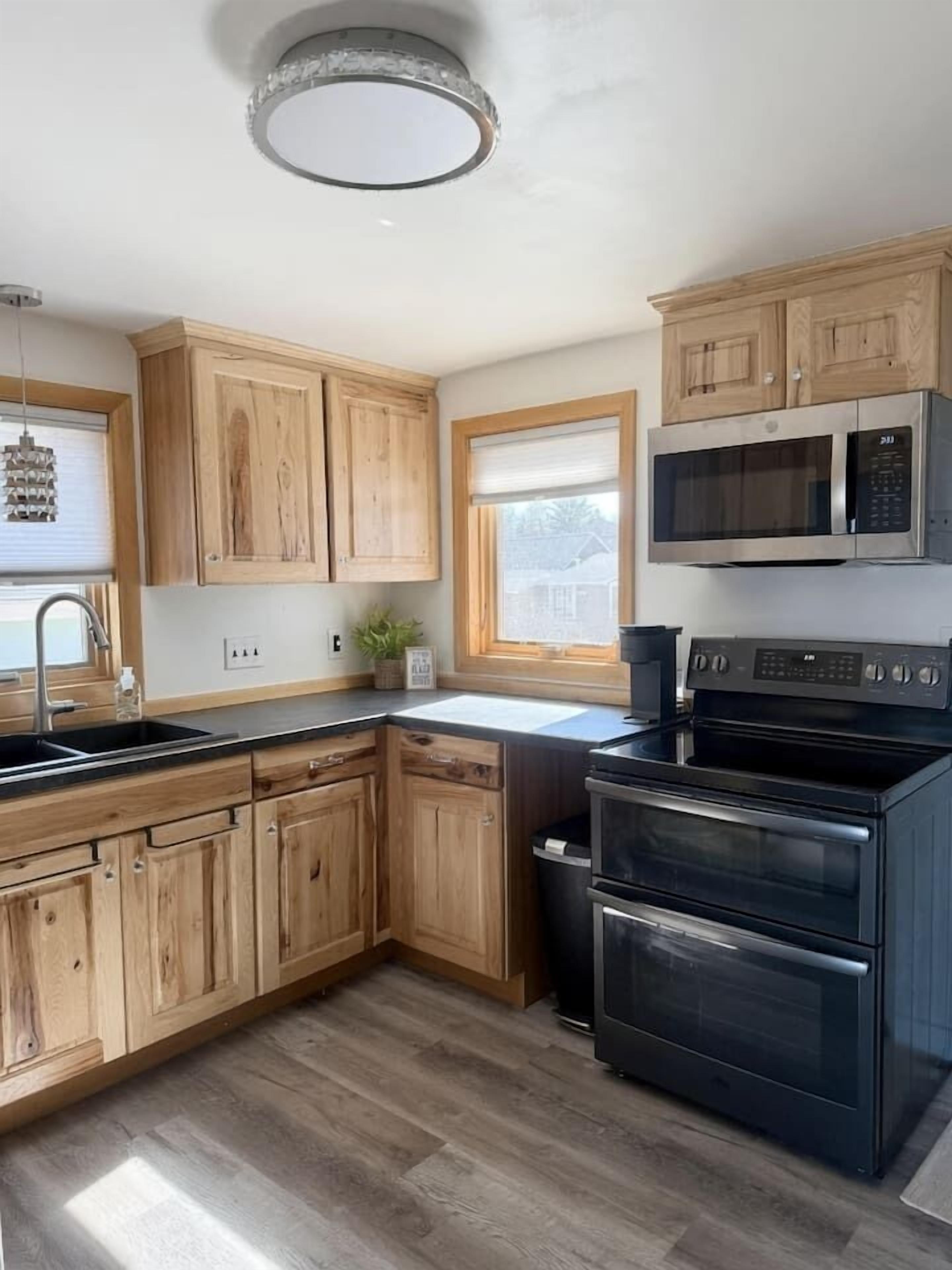 A kitchen with wooden cabinets, a black stove, and a microwave.