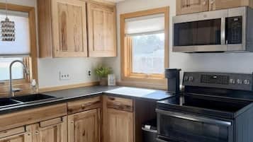 A kitchen with wooden cabinets, a black stove, and a microwave.