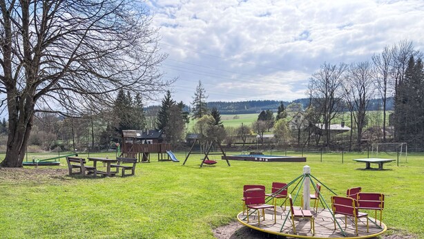 Ein Spielplatz mit Schaukeln, einer Rutsche und einem Karussell.