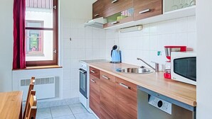 Eine kleine Küche mit Holzausstattung, einem Backofen, einer Mikrowelle und einem Spülbecken.