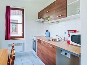 A compact kitchen with wooden cabinets, a built-in oven, a microwave, and a sink. - Green Valley Park Stárkov 18 by Interhome (Stárkov)