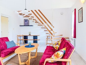 Ein Wohnzimmer mit einem roten Sofa, einem Holztisch und einer Treppe mit Holzbalken.
