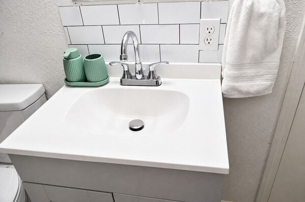 A bathroom with a white sink, green cups, and a white towel.