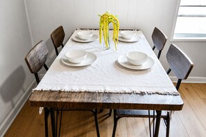 A dining table with white plates, a clear vase with yellow flowers, and wooden chairs. - Superhero Themed Family Home Near Downtown (Amarillo)