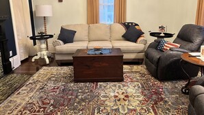 Un salon comprenant un canapé, une table basse, une table d’appoint, une lampe et un tapis à motifs.