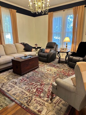 A living room with a sofa, two armchairs, a coffee table, and a chandelier.