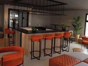 Eine moderne Küche mit Kochinsel, Barhocker und einer Sitzecke mit orangenen Stühlen.