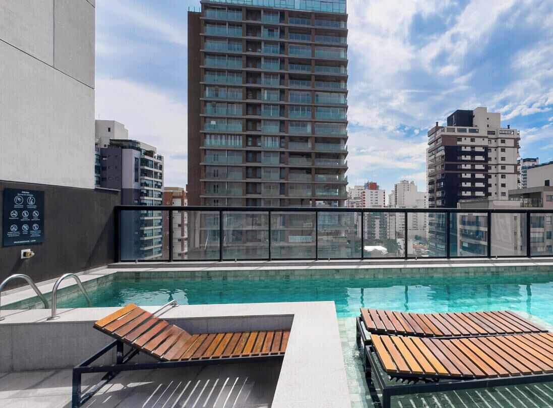 Ein Pool auf dem Dach mit Holzliegen und Blick auf die Stadt.
