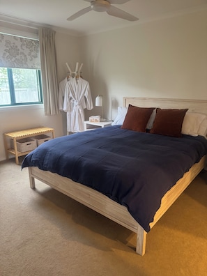 Un dormitorio con cama, mesita de noche, lámpara, bata y ventana.