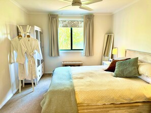 A hotel room with a bed, a bench, a robe rack, and a window with curtains. - Private cottage, stunning views, amongst vines, close to beaches and wineries (Tatachilla)