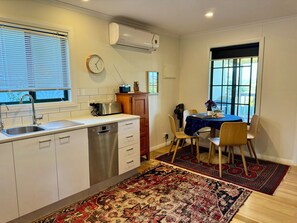 A compact kitchen with a dishwasher, a toaster, and a clock on the wall. - Private cottage, stunning views, amongst vines, close to beaches and wineries (Tatachilla)