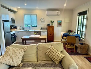 A compact living space with a kitchenette, a dining area, and a seating area with a sofa and chairs.