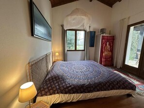A bedroom with a bed, a bedside lamp, a window, and a curtain. - Epona's House - LABATUT (LABATUT)