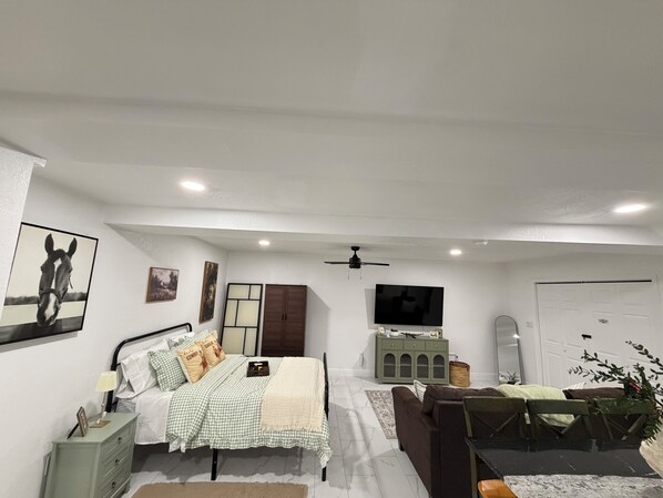 Un dormitorio con cama, mesita de noche, lámpara y televisor.