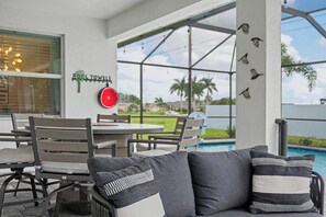 Un espace aménagé au bord de la piscine, avec un patio couvert, du mobilier d’extérieur et une vue sur la piscine.