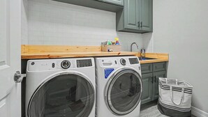 Ein kleiner Waschbereich mit zwei Waschmaschinen mit Frontlader, einer Holzarbeitsplatte und einem Waschbecken.