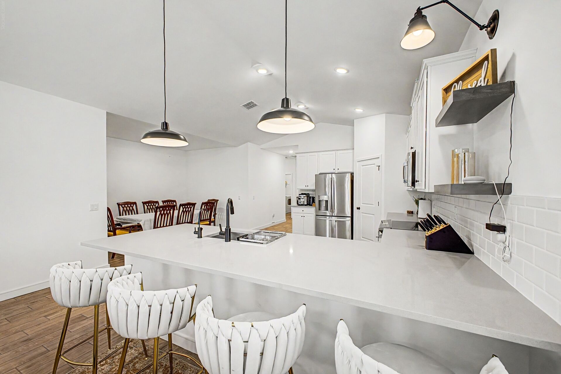 A modern kitchen with a central island, white cabinetry, and pendant lighting.