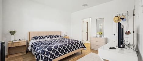 A bedroom with a bed, bedside tables, a desk, a mirror, and a wardrobe.
