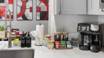 A modern kitchen with a coffee maker, jars of spices, and a sponge holder.