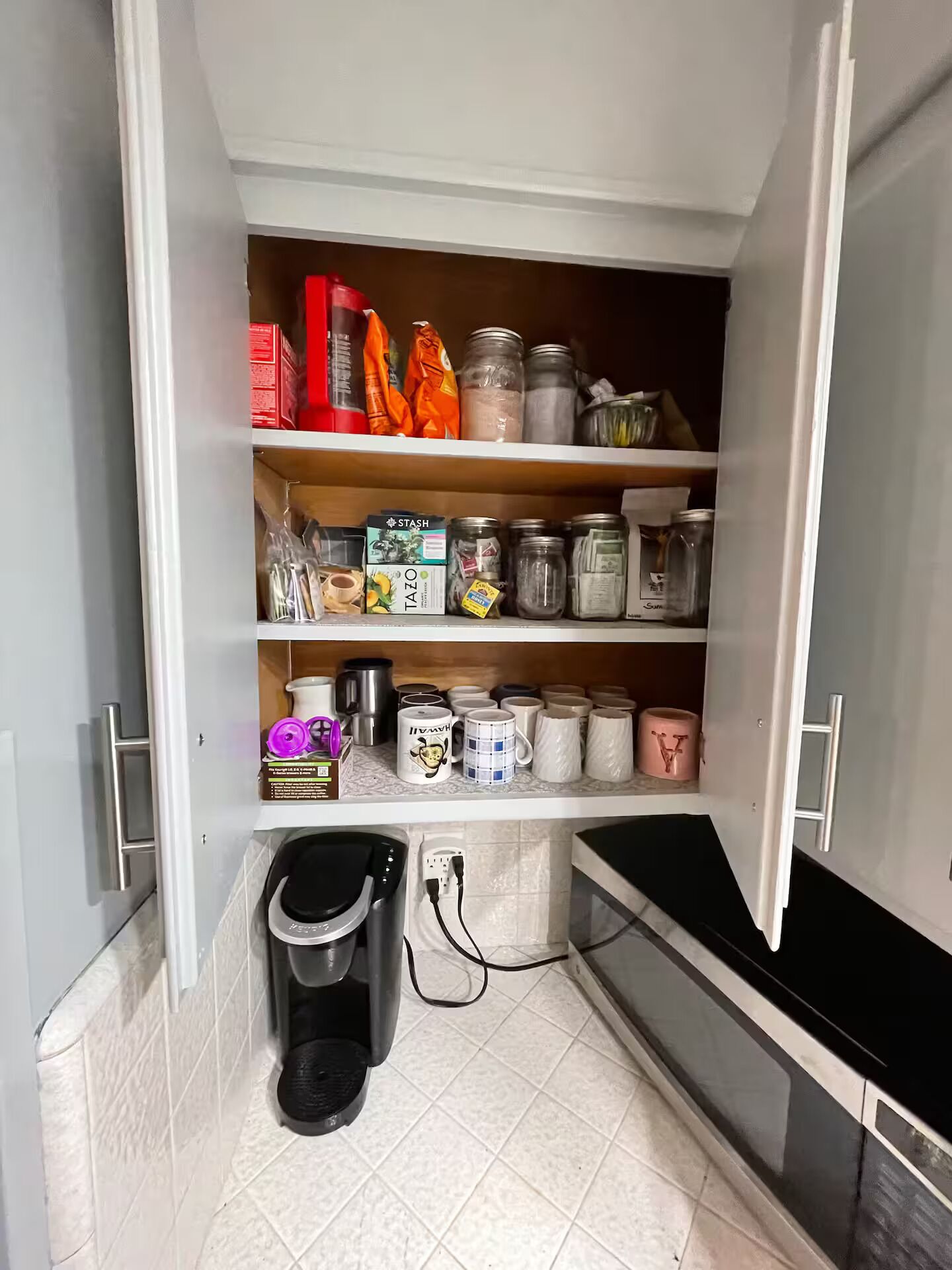 Una despensa de cocina con estantes llenos de frascos, cajas y utensilios de cocina.