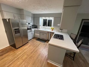 A modern kitchen with stainless steel appliances, a window, and a wooden floor. - - Yosemite Basecamp Lodge - (Mariposa)