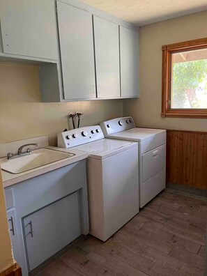 Una sala de bugaderia amb dues rentadores, un rentapeus i armaris.