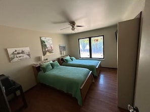 Habitació amb dos llits, ventilador al sostre i obra artística a les parets.