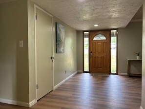 A hallway with a wooden door, a painting, and a small table with a plant. - - Yosemite Basecamp Lodge - (Mariposa)
