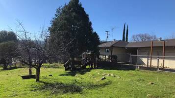 A residential property with a large tree, a fenced yard, and a house with a visible garage.