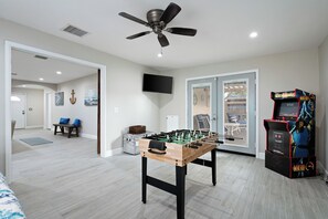 A room with a foosball table, a ceiling fan, a television, and a Mortal Kombat arcade game. - Spacious 5-bedroom house fully Furnished Private Pool – Extended Stays Welcome (Scottsdale)