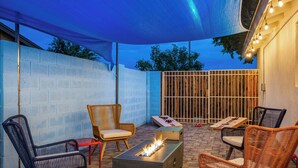 An outdoor patio area with wicker furniture, a fire pit, and a blue canopy. - Spacious 5-bedroom house fully Furnished Private Pool – Extended Stays Welcome (Scottsdale)