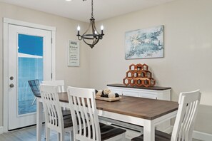 A dining area with a wooden table, white chairs, a chandelier, and a wall-mounted abstract painting. - Spacious 5-bedroom house fully Furnished Private Pool – Extended Stays Welcome (Scottsdale)