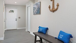 A hallway with a white door, a bench with two pillows, and a wall-mounted anchor decoration. - Spacious 5-bedroom house fully Furnished Private Pool – Extended Stays Welcome (Scottsdale)