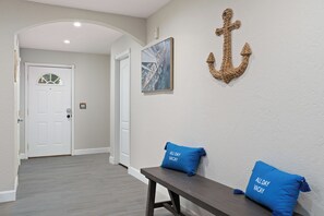 A hallway with a white door, a bench with two pillows, and a wall-mounted anchor decoration. - Spacious 5-bedroom house fully Furnished Private Pool – Extended Stays Welcome (Scottsdale)