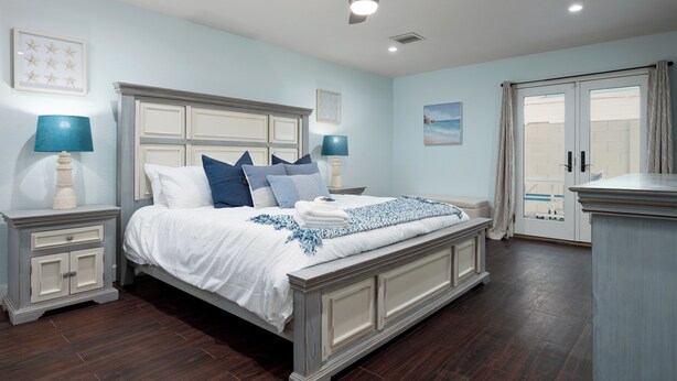 A bedroom with a large bed, two bedside tables, a ceiling fan, and a view of the outside. - Spacious 5-bedroom house fully Furnished Private Pool – Extended Stays Welcome (Scottsdale)