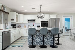 A modern kitchen with white cabinetry, stainless steel appliances, and a central island with bar stools. - Spacious 5-bedroom house fully Furnished Private Pool – Extended Stays Welcome (Scottsdale)