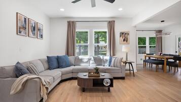 A modern living room with a sectional sofa, a coffee table, and a dining area with a table and chairs.
