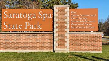 A sign for Saratoga Spa State Park listing amenities like the Giedon Putnam Hotel, Hall of Springs, Automobile Museum, Museum of Dance, and Golf Courses & Pools.