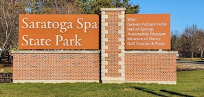 A sign for Saratoga Spa State Park listing amenities like the Giedon Putnam Hotel, Hall of Springs, Automobile Museum, Museum of Dance, and Golf Courses & Pools.