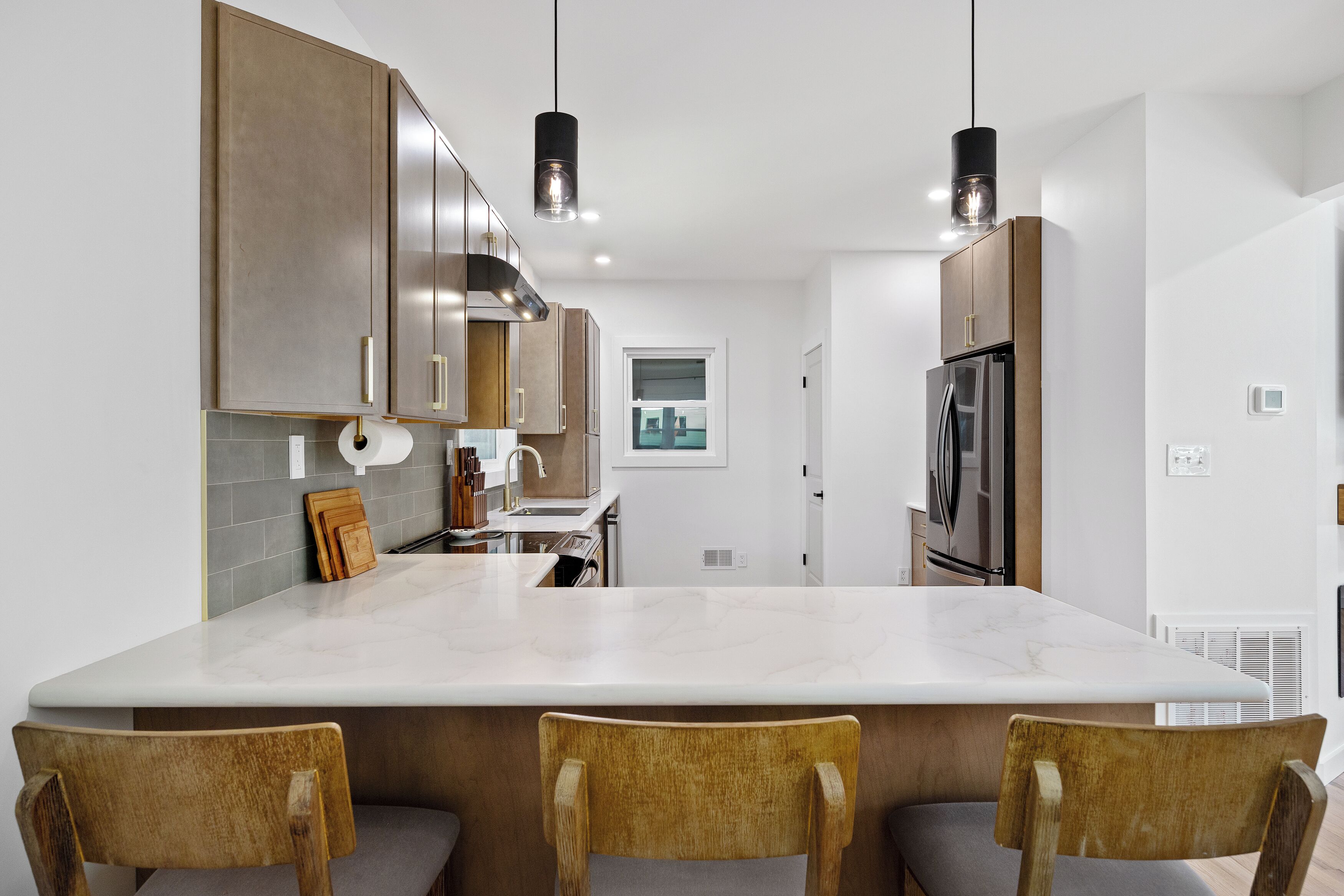 Una cocina moderna con una isla grande, electrodomésticos de acero inoxidable y sillas de madera.