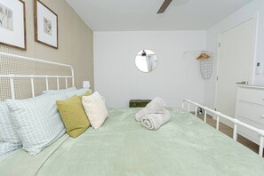 A bedroom with a bed, pillows, a round mirror, a dresser, and a wall with framed pictures. - Stylish 1BR Laguna Beach Walk to Dominicus Beach (Dominicus)