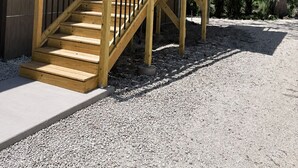 A wooden staircase leading to a covered outdoor area with a view of a house and trees. - Angler’s Hideaway: Your Peaceful Escape for Fishing, Fun & Relaxation (Homosassa)