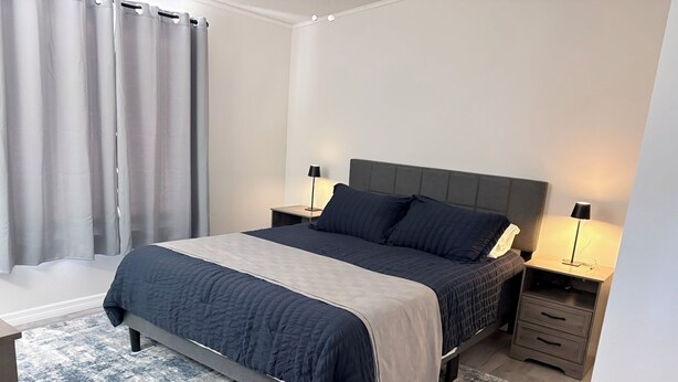 A modern bedroom with a bed, bedside tables, and a nightstand. - Angler’s Hideaway: Your Peaceful Escape for Fishing, Fun & Relaxation (Homosassa)